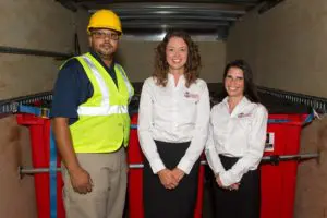 Employees in front of bins for medical waste disposal.