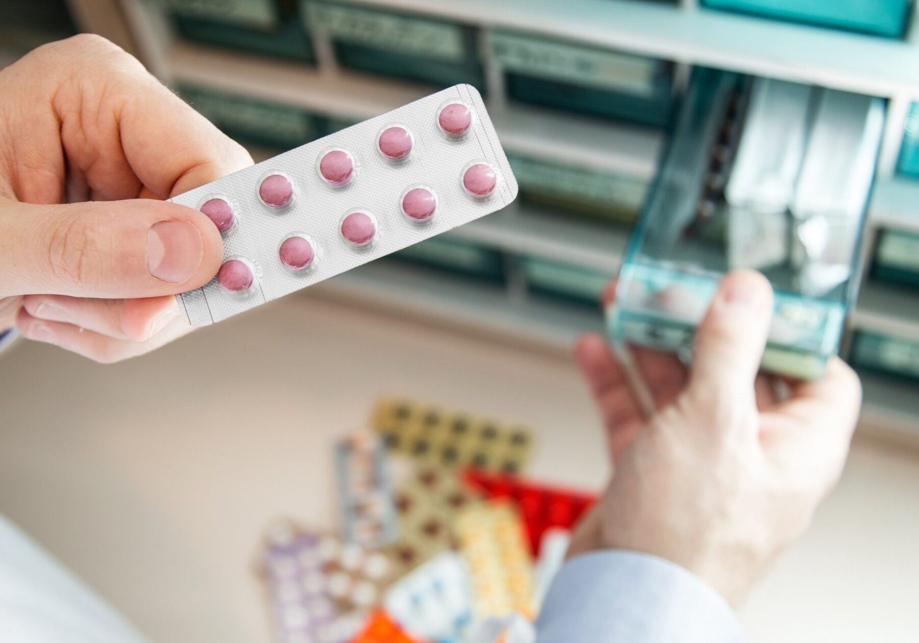 Pharmacist handling blister packs of pills, highlighting safe practices for disposing pharmaceutical waste.
